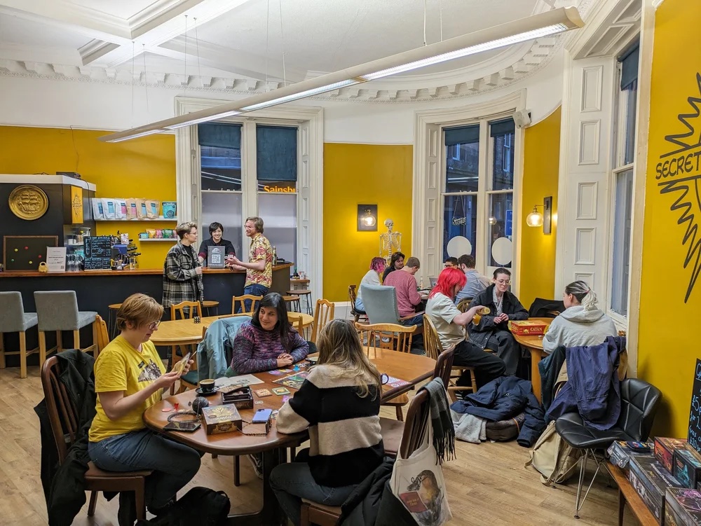 Inside Secret Solstice Games — golden-yellow walls, players at tables